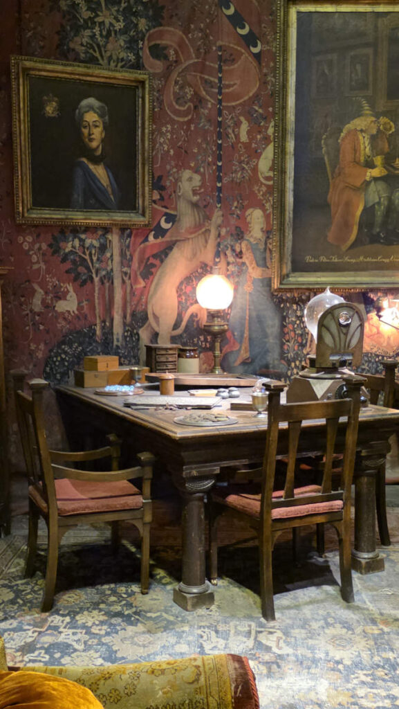 Details im Gryffindor-Gemeinschaftsraum mit Tisch, Gemälden und Wandteppichen in der Harry Potter Studio Tour London.