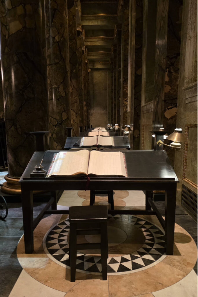 Aufgereihte Schreibpulte mit aufgeschlagenen Büchern im Gringotts-Banksaal der Harry Potter Studio Tour London.