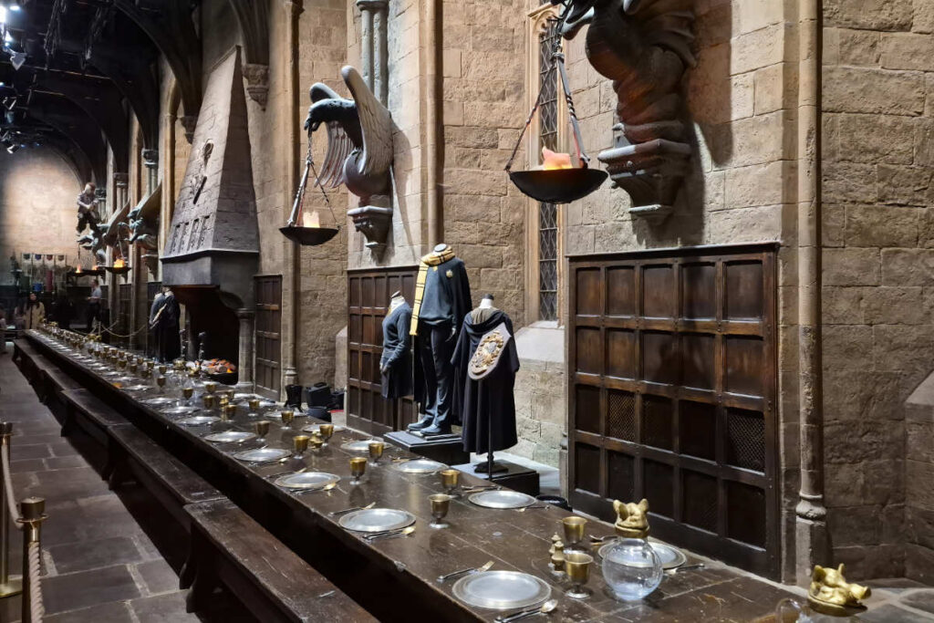 Gedeckte Tische und Hogwarts-Kostüme in der Großen Halle der Harry Potter Studio Tour London.