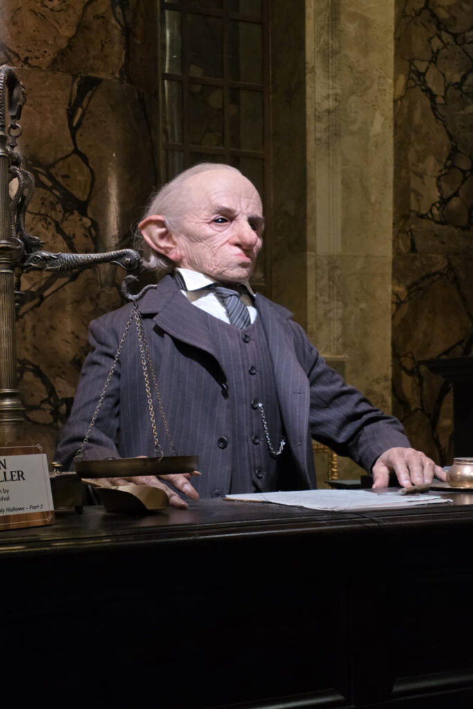 Ein Gringotts-Kobold hinter dem Kassenschalter im Banksaal der Harry Potter Studio Tour London.