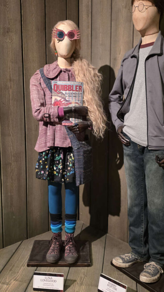 Nahaufnahme des Kostüms von Luna Lovegood mit Radieschenohrringen und Quibbler in der Harry Potter Studio Tour London.