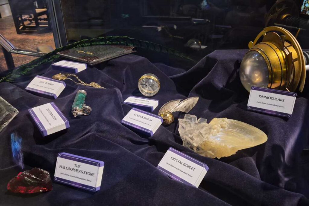 Requisiten-Vitrine mit dem Stein der Weisen, dem Goldenen Schnatz, dem Zeitumkehrer und weiteren Originalen in der Harry Potter Studio Tour London.
