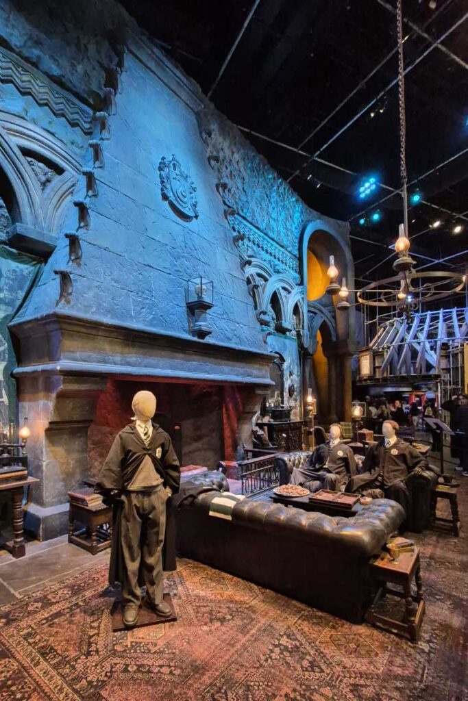 Der Slytherin-Gemeinschaftsraum mit dunklem Leder, Steinwänden und Slytherin-Kostümen in der Harry Potter Studio Tour London.