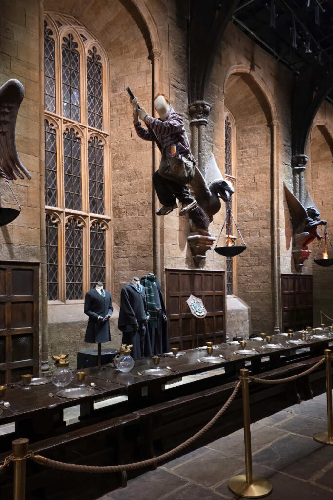 Ein Weasley-Zwilling auf dem Besen in der Großen Halle beim saisonalen Feature Magical Mischief in der Harry Potter Studio Tour London.
