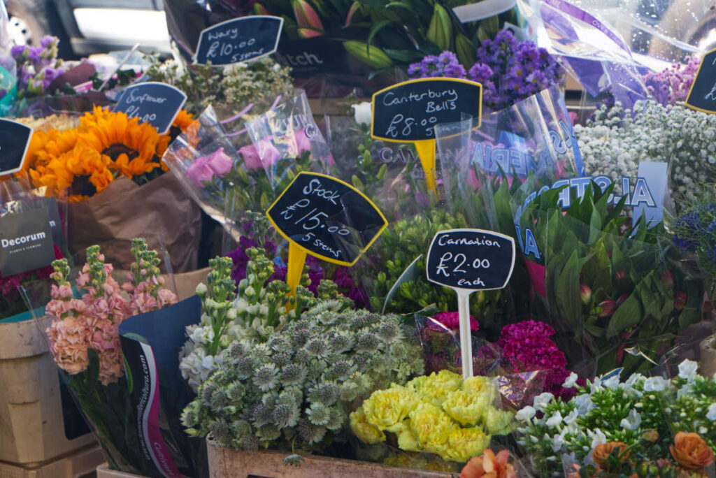Bunter Blumenstand am Portobello Road Market mit Sonnenblumen, Rosen, Nelken und mehr