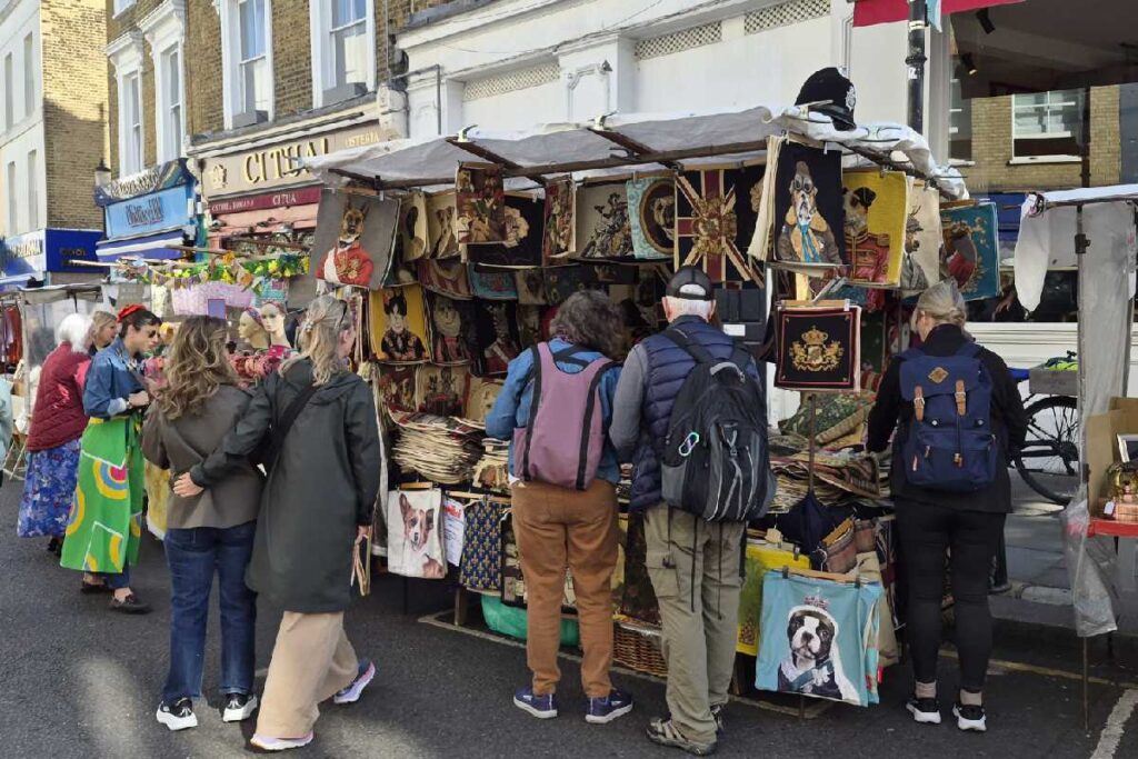 Marktstand am Portobello Road Market mit Kunstdrucken von Hundeporträts, Besucher stöbern