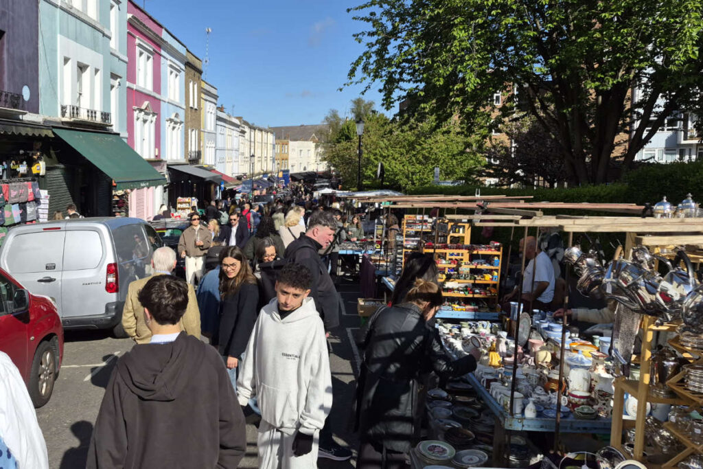 Portobello Road in Notting Hill London mit bunten Häuserfassaden und belebtem Straßenmarkt
