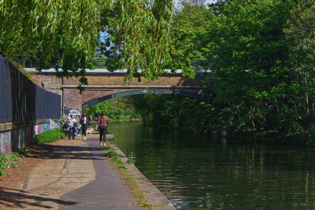 Backsteinbrücke mit Bäumen und Spaziergängern am Regent's Canal London