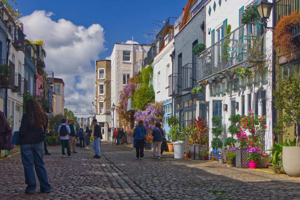 St. Luke's Mews in Notting Hill mit Besuchern, lila Glyzinien an der Fassade und Kopfsteinpflaster