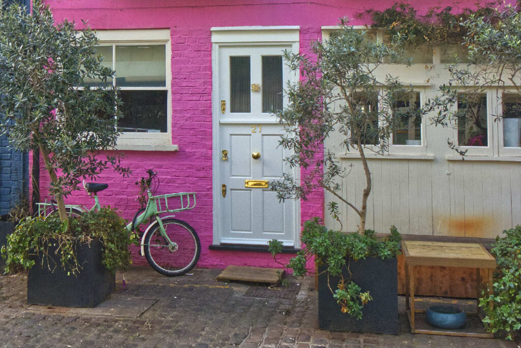 Haus Nr. 27 in St. Luke's Mews mit pinker Fassade, weißer Tür und grünem Fahrrad davor