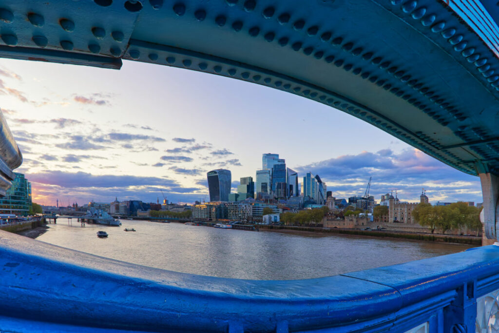 Skyline der City of London durch die Stahlkonstruktion der Tower Bridge gerahmt, Tower of London im Bild